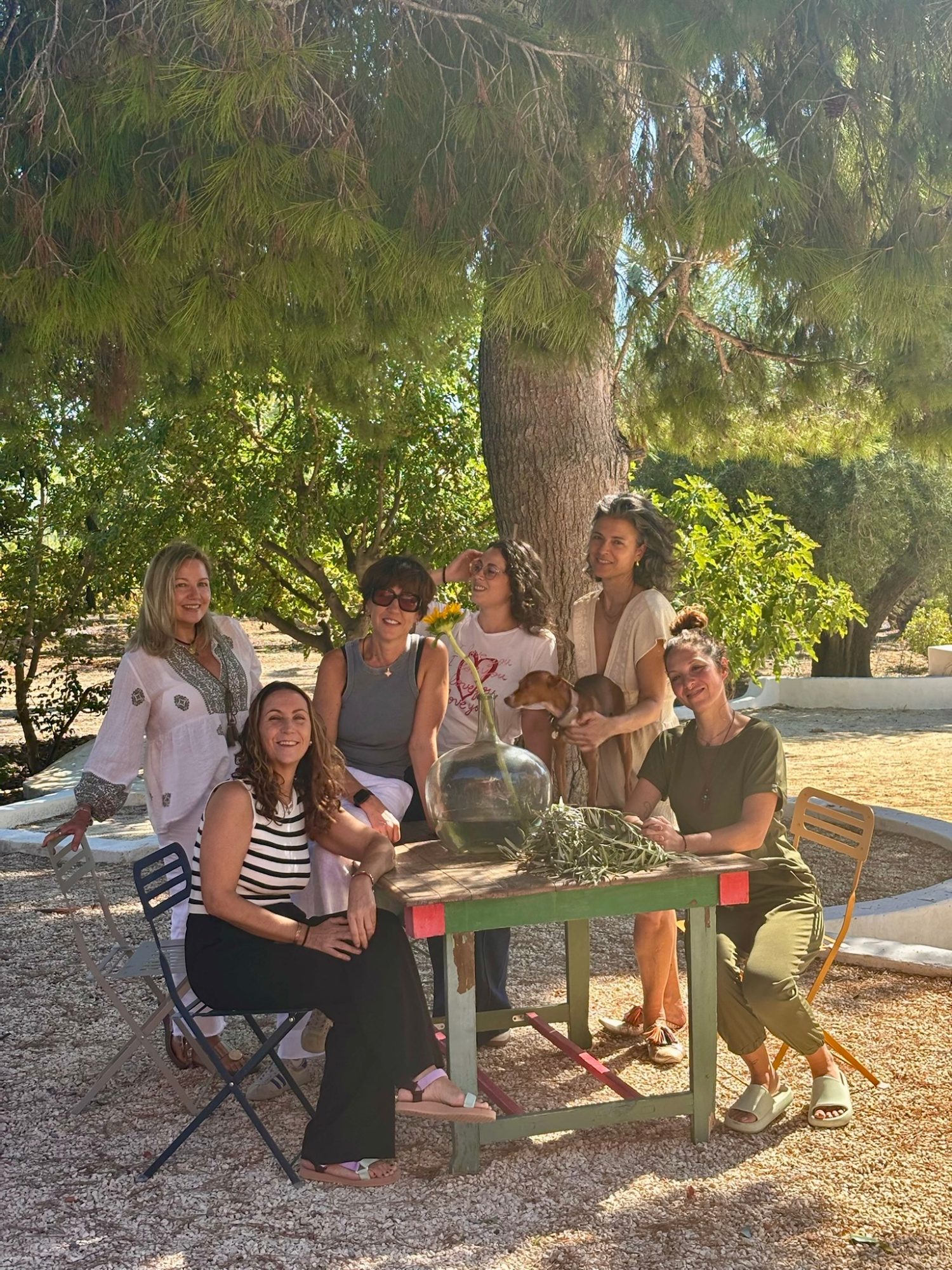 Grupo de mujeres sonriendo bajo un árbol en el jardín de Cal Roig